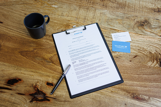 Vertrag mit Stift, daneben Visitenkarten und Kaffeetasse